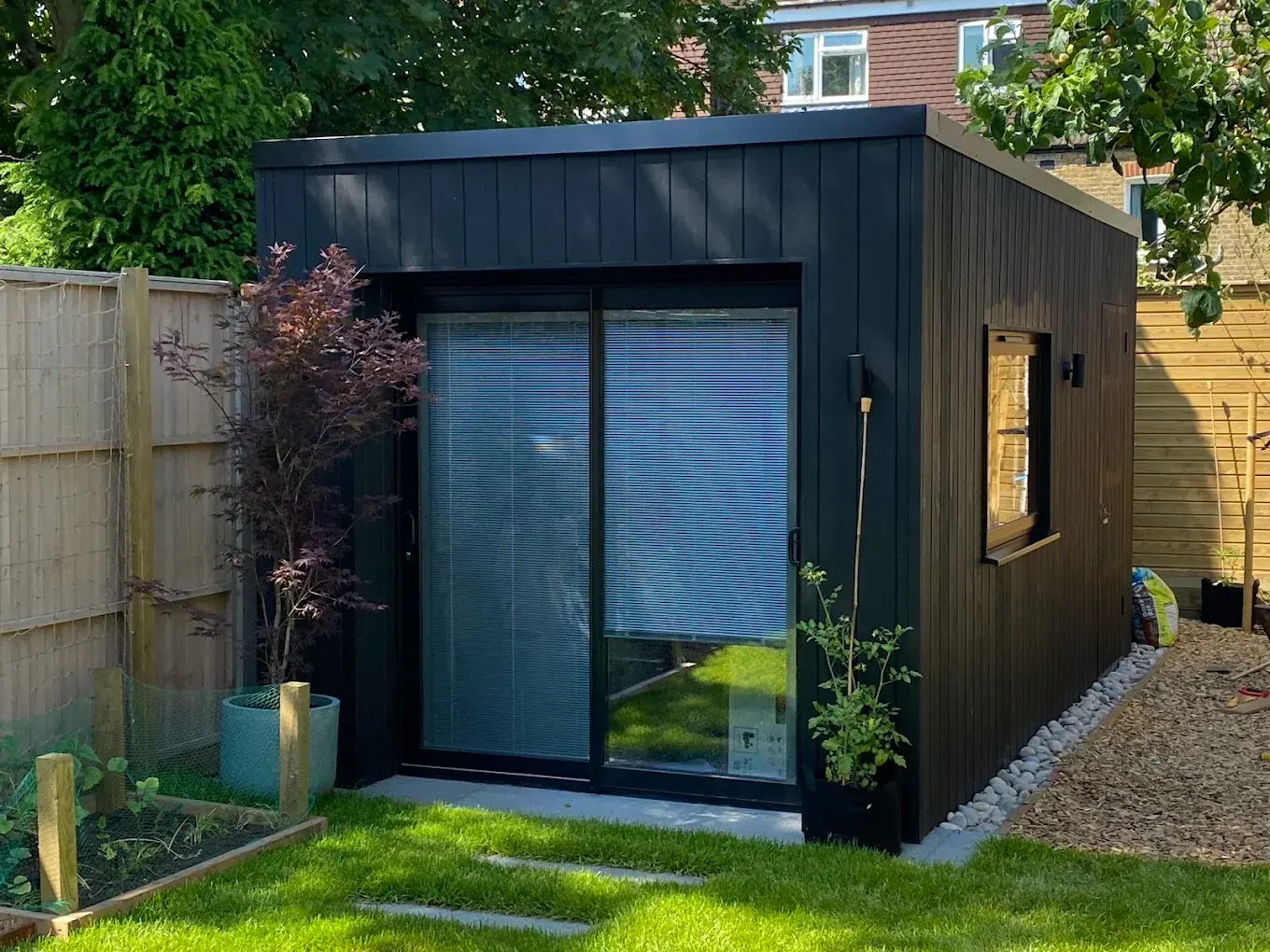 A finished black-clad garden studio with a wide sliding door.