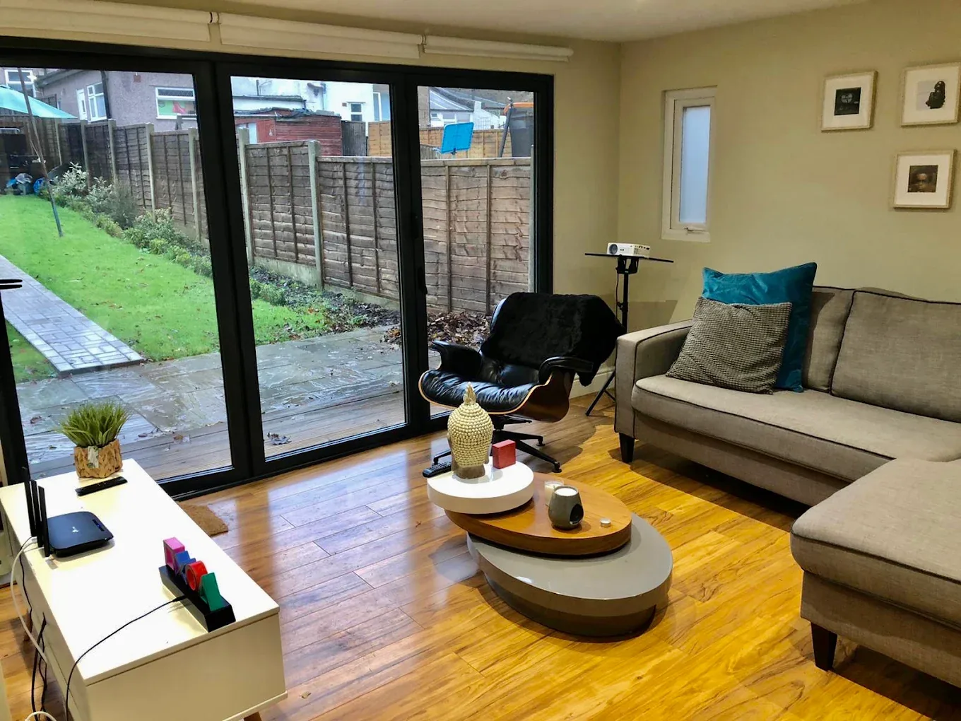 Inside a finished garden room: sofa, lounge chair and wide glazed doors onto the garden.